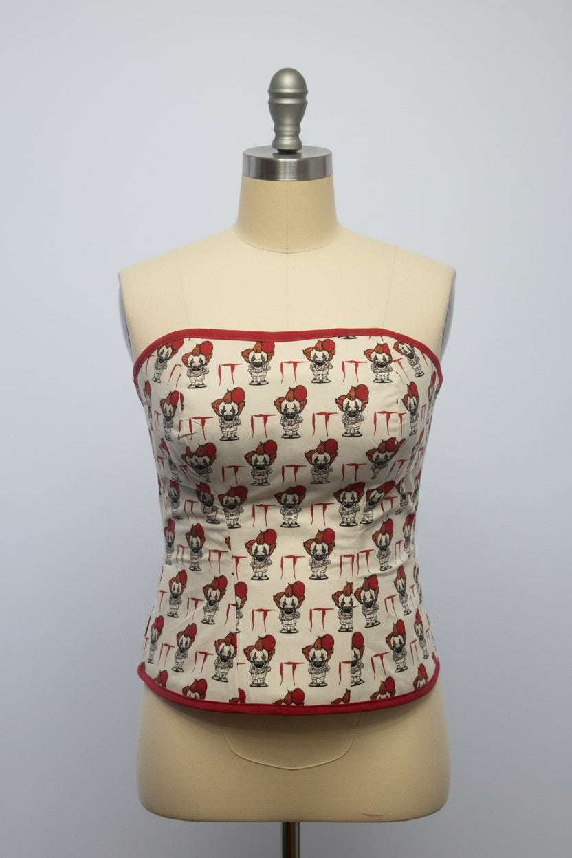 A beige and red cotton corset with character patterns and organza ribbon lacing up the back.