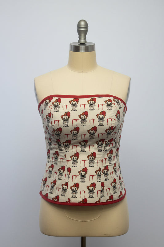 A beige and red cotton corset with character patterns and organza ribbon lacing up the back.